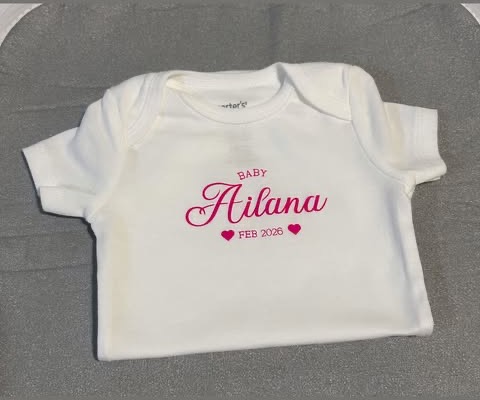White baby onesie with pink custom name and date