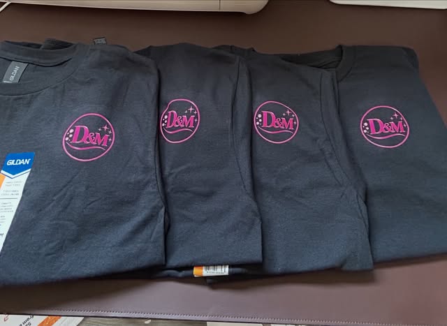 Row of black business shirts with small pink logo
