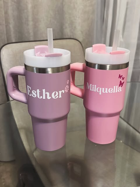 Two personalized pink and purple tumblers with names and flowers